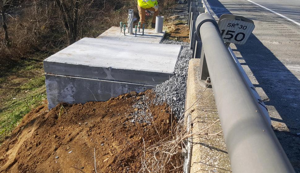 Highway construction worker inspects signage foundation