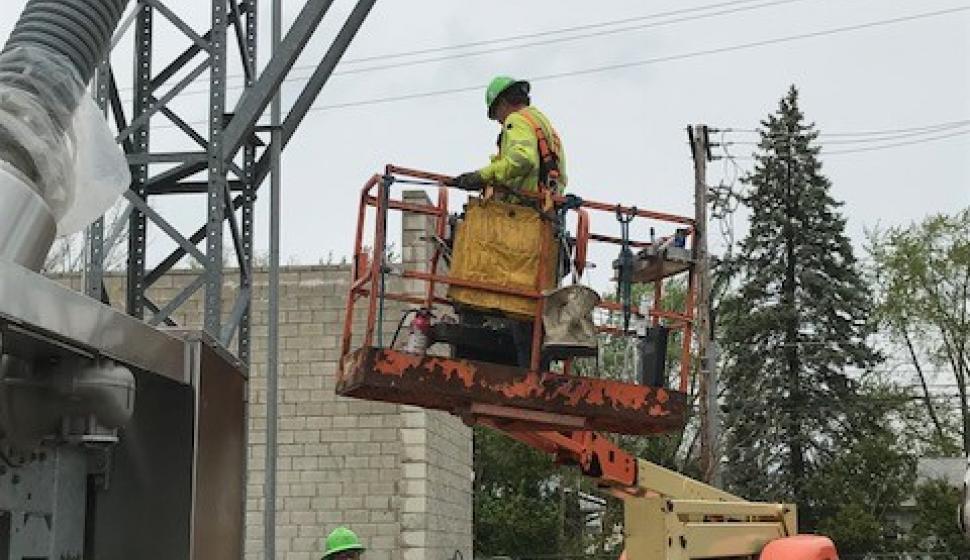 Outside lineman on a lift, preparing to work on overhead steel support structure